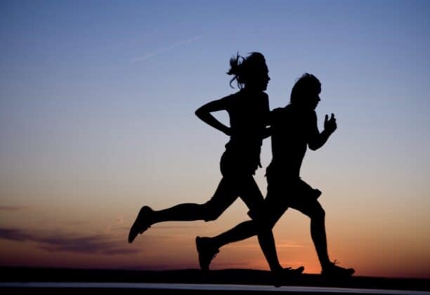 Silhouette of couple running at sunset.