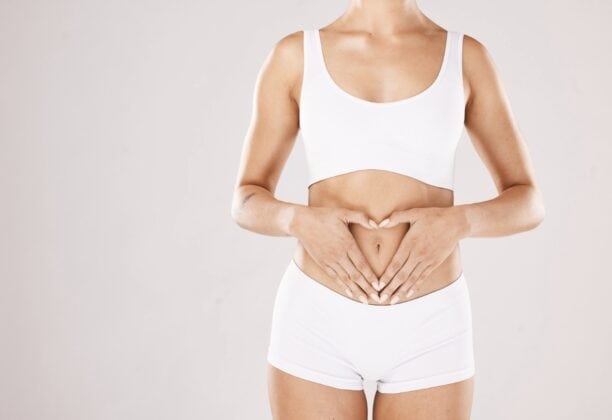 A woman focused on her gut health, with her hands on her stomach.