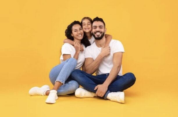 A happy family sitting together on a yellow background - royalty-free footage.