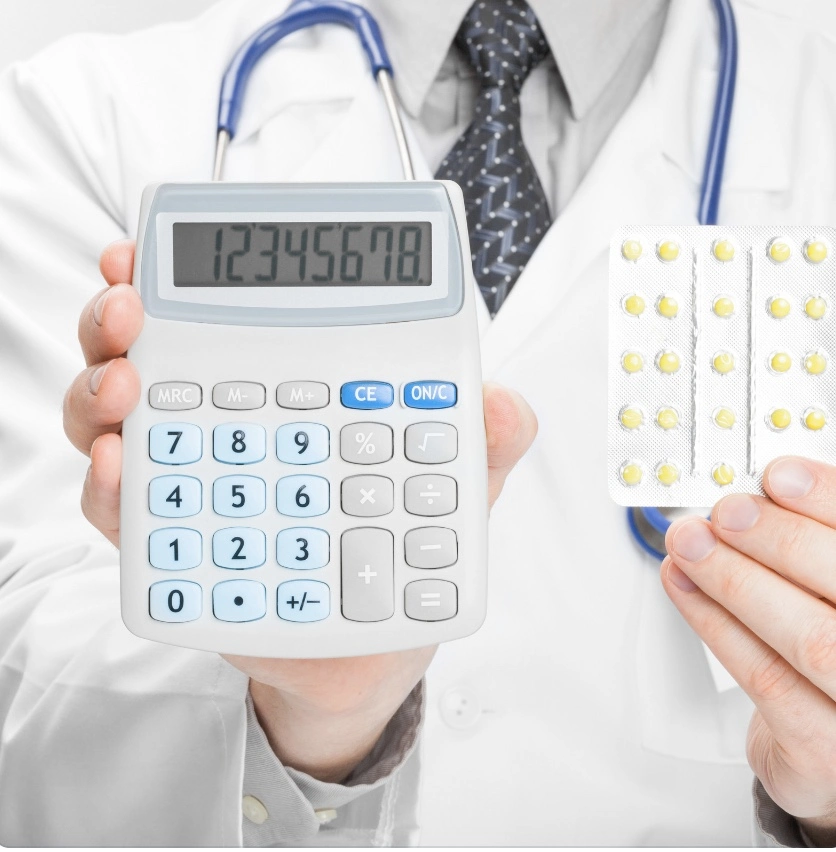 A doctor using an Rx savings card while holding a calculator and pills.